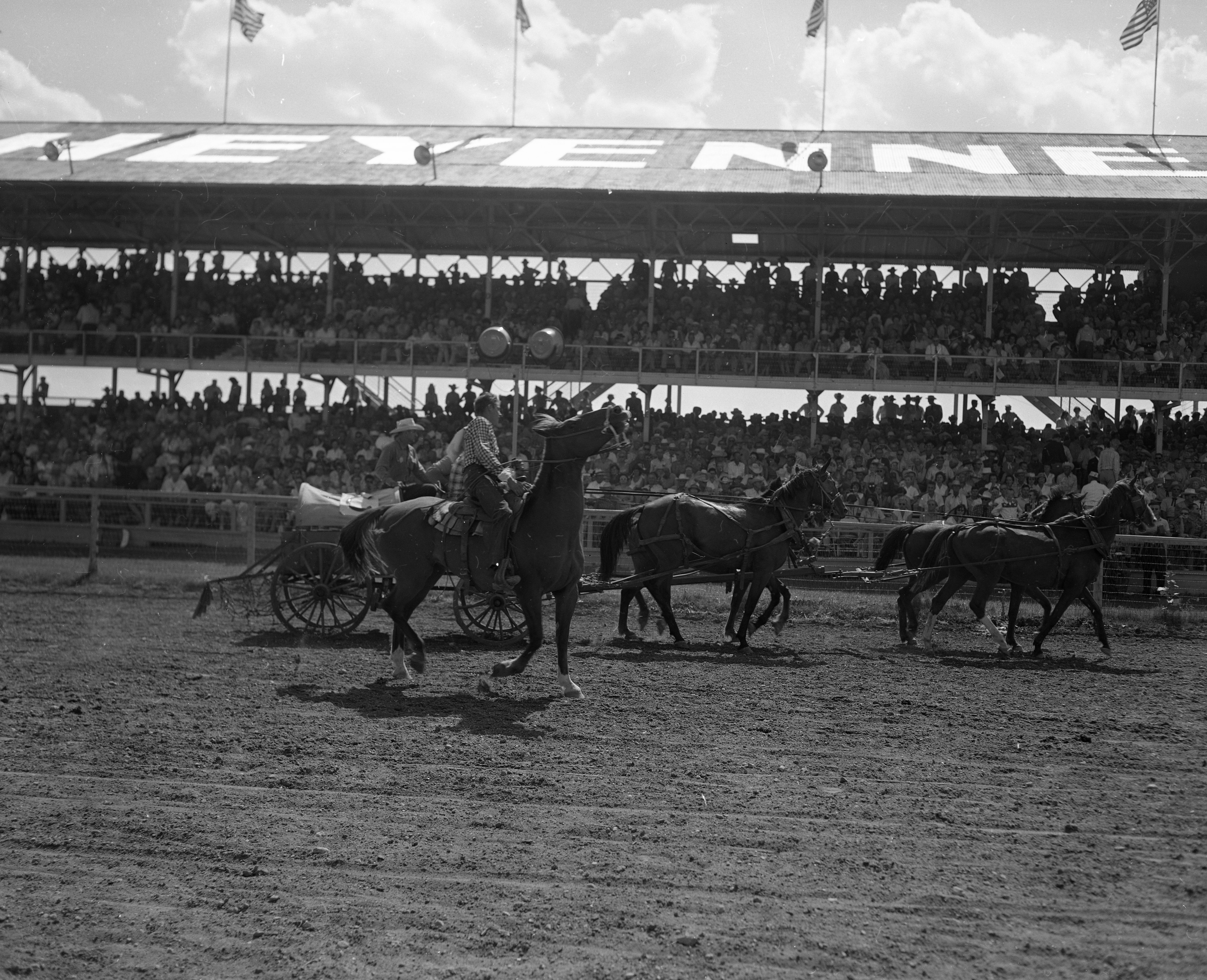 Man on horse next to wagon during Frontier Days celebration.