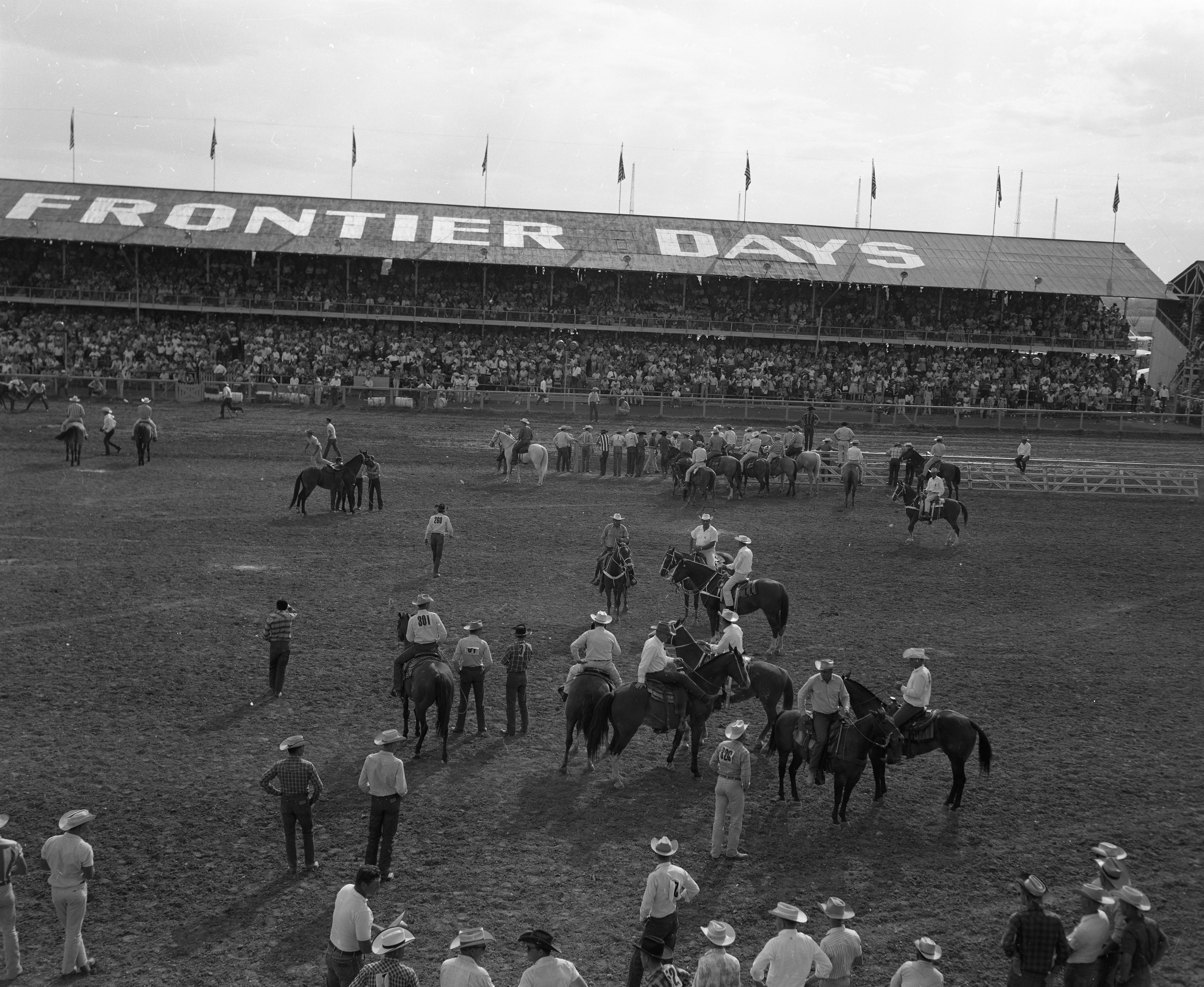 Frontier Days stands with people and horses gathered in the arena.